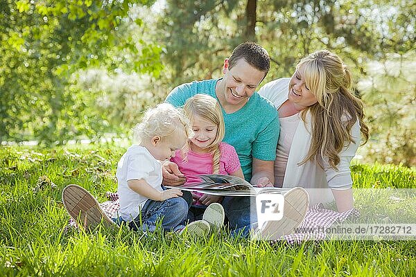 Young family enjoys reading a book together in the park