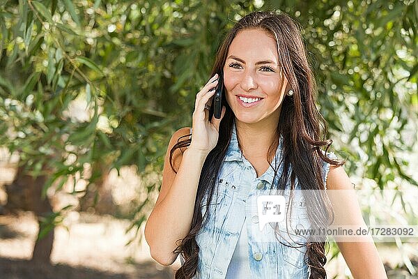 Attractive happy mixed-race young female talking on cell phone outside