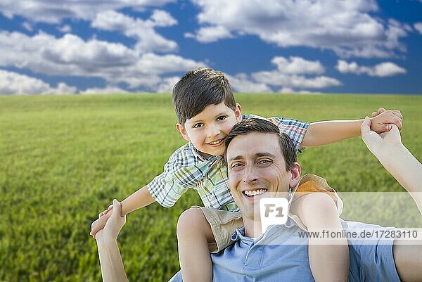 Glückliche gemischtrassige Vater und Sohn spielen Huckepack auf Grasfeld