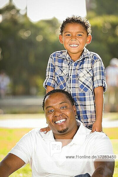Glücklicher afrikanischer amerikanischer Vater und gemischtrassiger Sohn spielen im Park