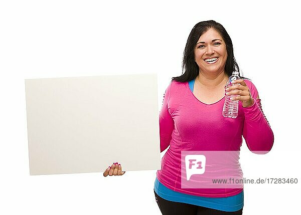 Attraktive mittlere Alter hispanische Frau in Training Kleidung mit Wasserflasche und leeren weißen Schild vor einem weißen Hintergrund