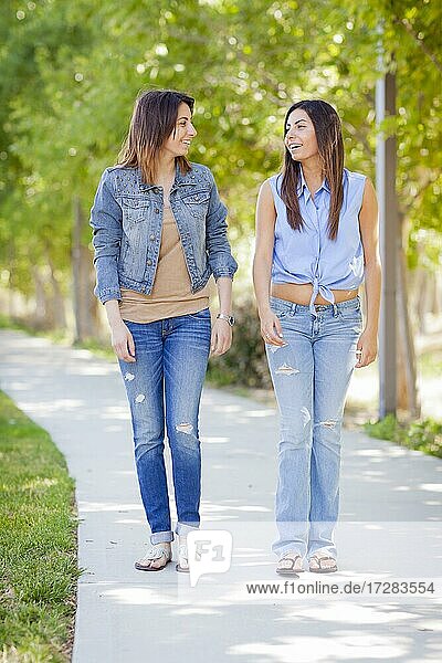Young adult mixed-race twin sisters walking together outside