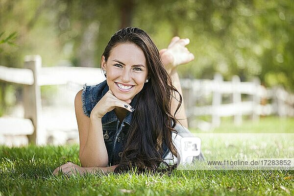 Attractive mixed-race girl portrait laying in grass outdoors