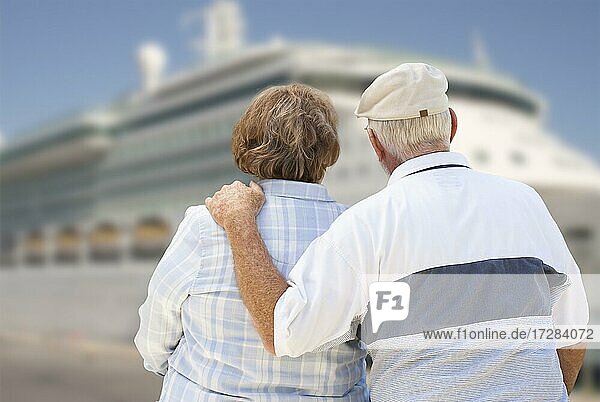 Senior couple on shore facing and looking at docked cruise ship