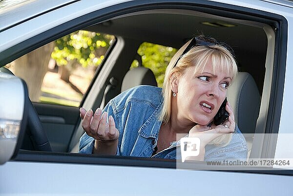 Concerned blonde woman using cell phone while driving