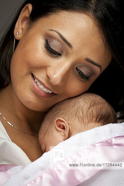 Young attractive ethnic woman holding her newborn baby under dramatic lighting