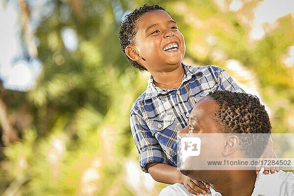 Glücklicher gemischtrassiger Vater und Sohn spielen im Park