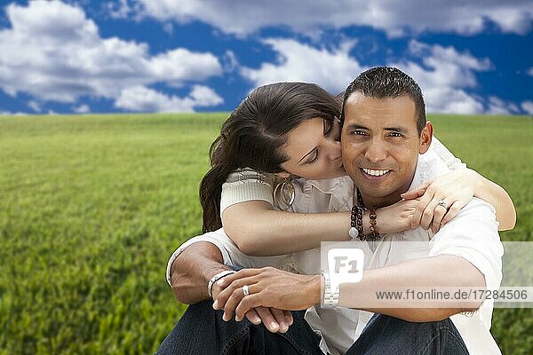 Happy hispanic couple sitting in grass field