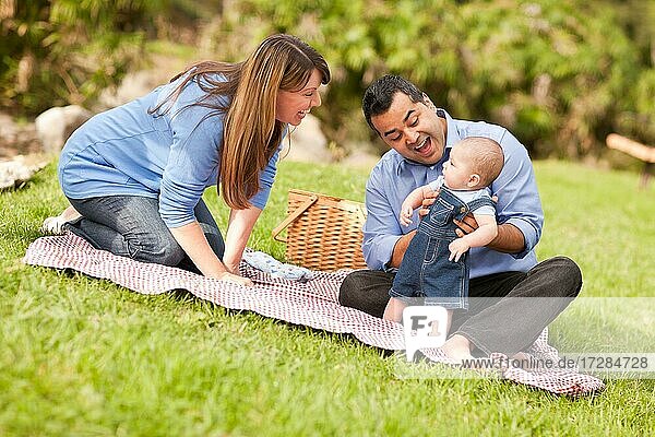 Happy mixed-race family having a picnic and playing in the park