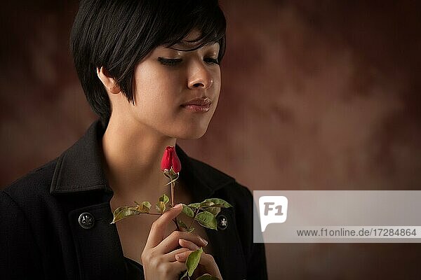 Pretty multiethnic young adult woman holding a single rose portrait with selective focus