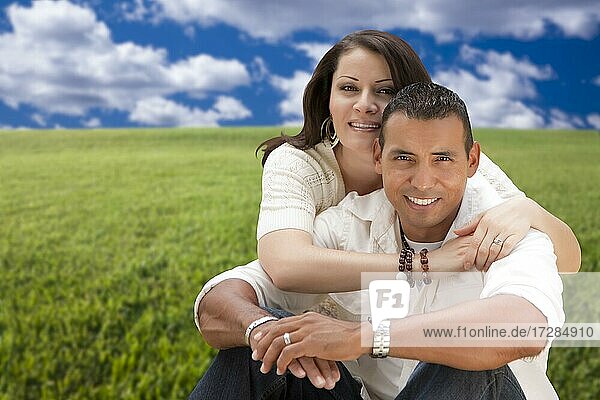 Glückliche hispanische Paar sitzt in Wiese