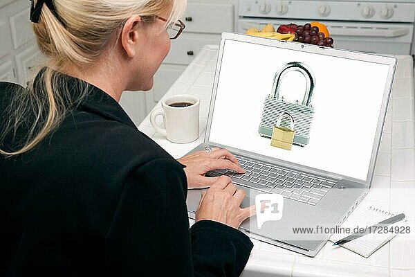 Frau in der Küche mit Laptop mit hoher Sicherheitsstufe. Bildschirm kann leicht für Ihre eigene Nachricht oder Bild verwendet werden