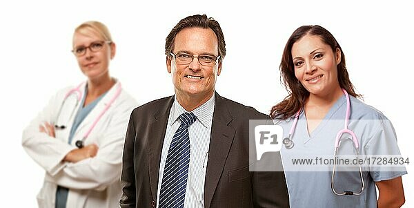 Lächelnde Geschäftsmann in Suite und Krawatte  während weibliche Arzt und Krankenschwester stehen hinter vor einem weißen Hintergrund