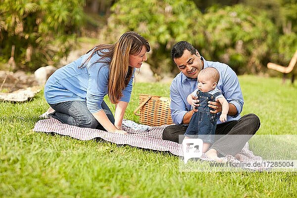 Glückliche gemischtrassige Familie  die ein Picknick macht und im Park spielt