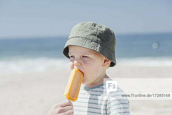 Vater füttert seinen süßen Sohn am Strand mit Eiscreme