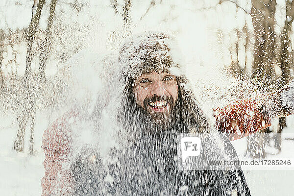 Frau wirft Schnee auf glücklichen Mann im Wald