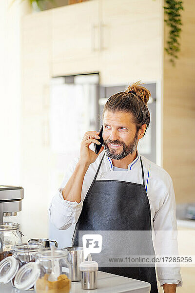 Männlicher Koch  der in einem Restaurant mit seinem Handy telefoniert