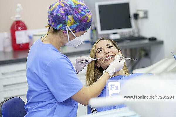 Zahnärztin untersucht die Zähne eines Patienten in einer Klinik während der Pandemie
