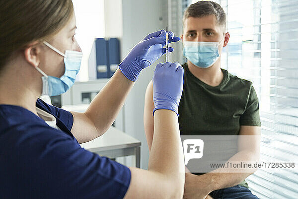 Eine Mitarbeiterin des Gesundheitswesens bereitet eine Impfstoffspritze für einen männlichen Patienten im Zentrum vor