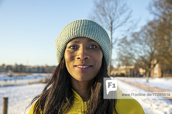 Schöne lächelnde Frau mit blauer Strickmütze im Winter