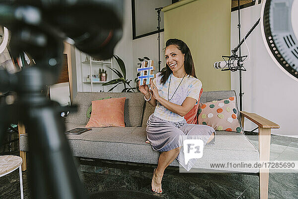 Lächelnde Frau zeigt Hashtag-Symbol beim Vloggen zu Hause