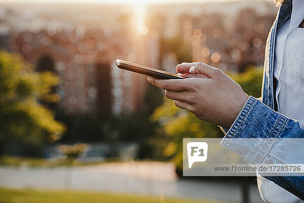 Frau benutzt Smartphone bei Sonnenuntergang