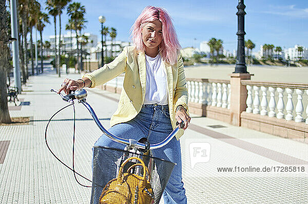 Lächelnde Frau auf dem Fahrrad sitzend an der Promenade