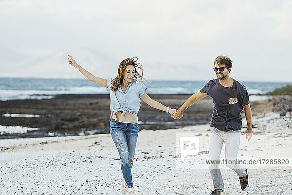 Couple holding hands wile running on beach