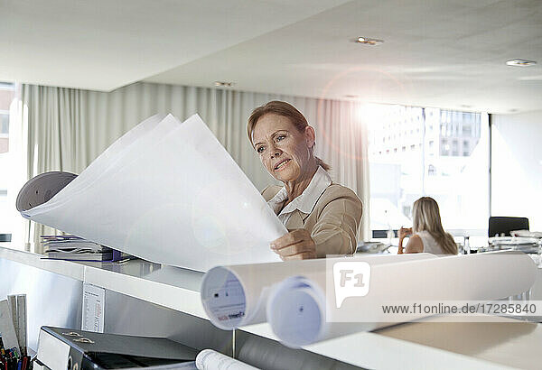 Geschäftsfrau mit Blick auf Blaupausen im Büro