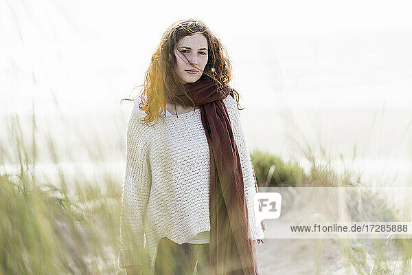 Young woman wearing scarf standing in dunes during sunny day