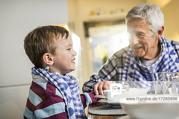 Smiling grandson holding hand of grandfather at home