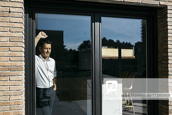 Male freelancer leaning on glass window
