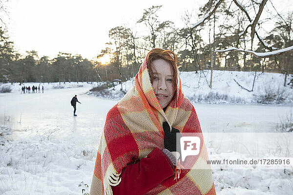 Smiling woman covering with blanket during winter