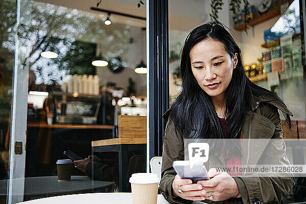 Frau benutzt Mobiltelefon in einem Cafe