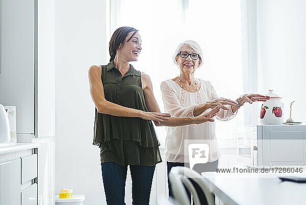Glückliche Frau mit Großmutter tanzt in der Küche