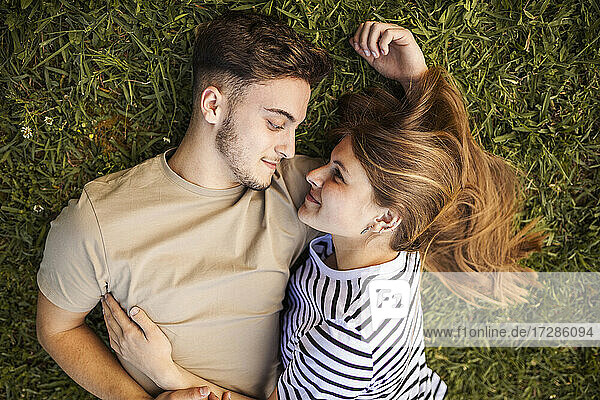 Lächelndes romantisches Paar im Gras liegend