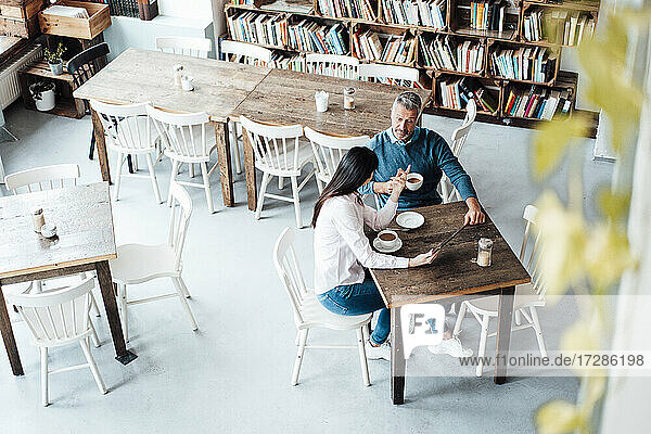 Männliche und weibliche Besitzer unterhalten sich bei einem Kaffee im Café