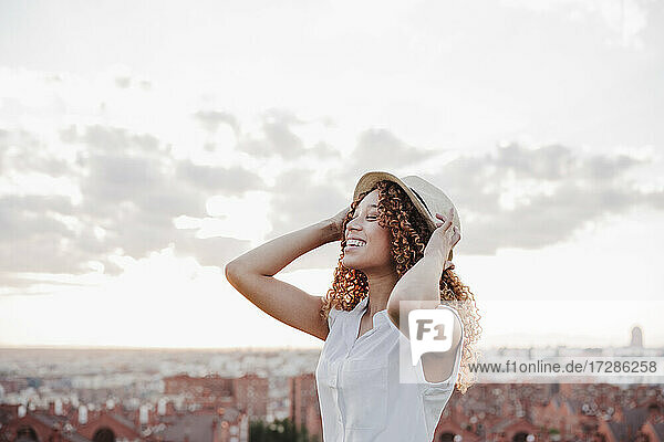 Glückliche hispanische Frau mit Hut vor dem Himmel