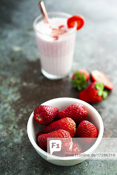 Bowl of fresh strawberries and glass of strawberry smoothie