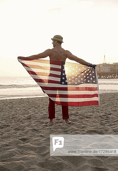 Young man holding flag on Santa Monica beach
