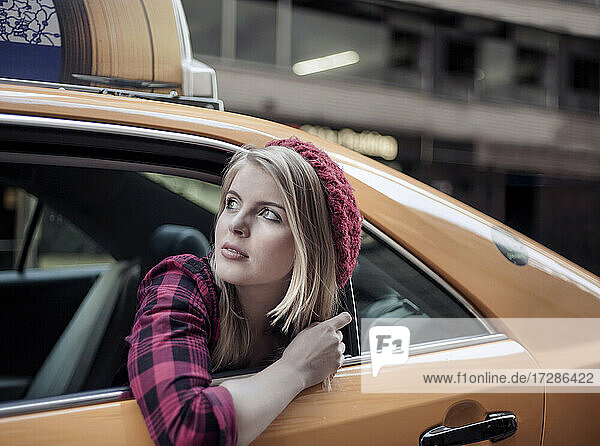 Beautiful woman wearing beret looking away through taxi window