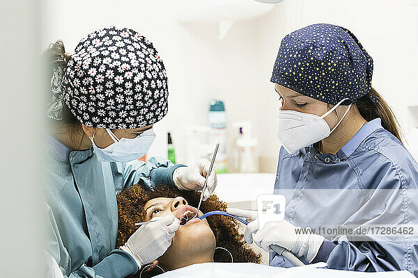 Female patient receiving treatment from dentists at clinic