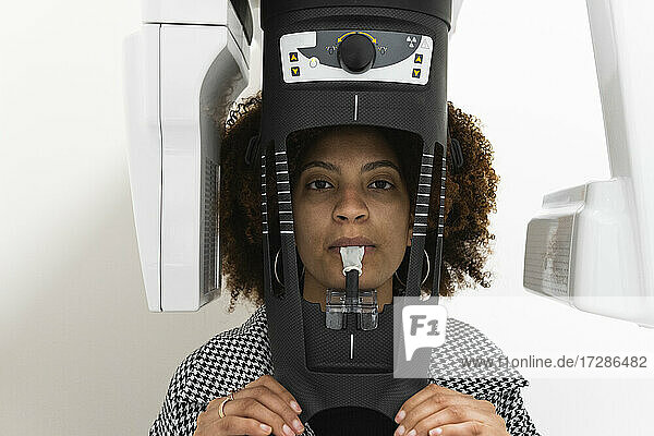 Female patient standing at dental x-ray machine in clinic