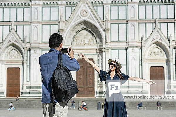 Mann fotografiert weibliche Touristin durch die Kamera vor der Basilika Santa Croce in Florenz  Italien