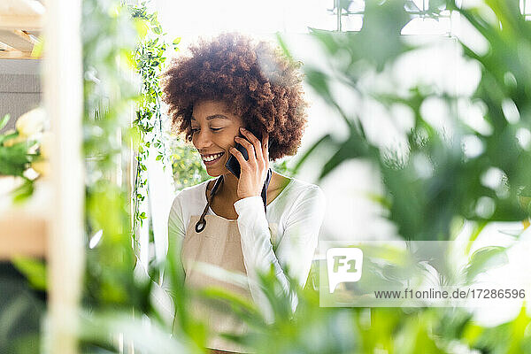 Weibliche Blumenhändlerin  die in einem Blumenladen mit ihrem Handy telefoniert