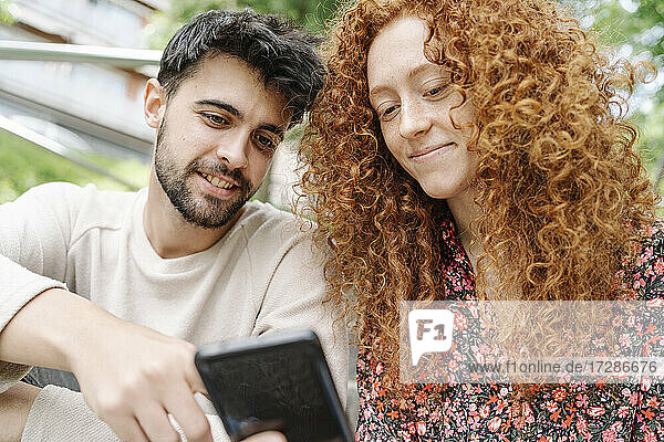 Junger Mann mit Freundin bei der Nutzung eines Smartphones