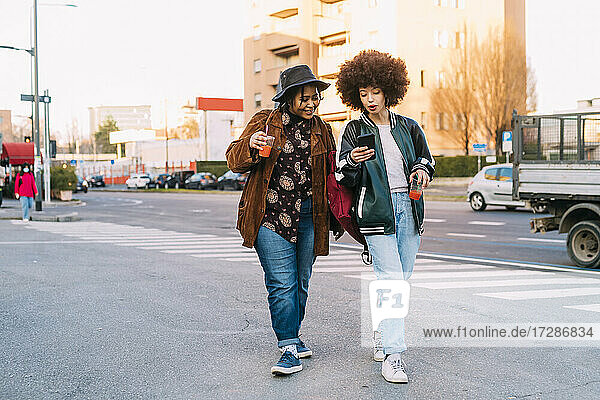 Young women using mobile phone while walking on phone