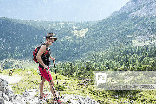 Smiling woman standing on rock while hiking on mountain