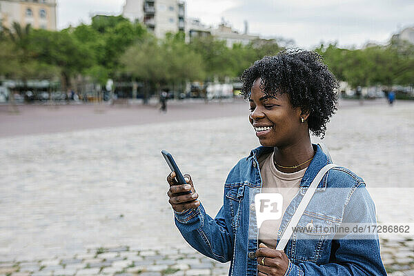 Lächelnde Frau mit Smartphone in der Stadt