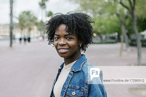 Lächelnde junge Frau mit Afrofrisur in der Stadt